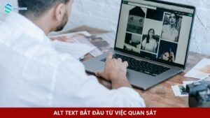 Người biên tập xem ảnh trên laptop cạnh các bản in và máy ảnh