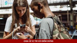 Hai người mang ba lô cùng kiểm tra điện thoại ở nhà ga.