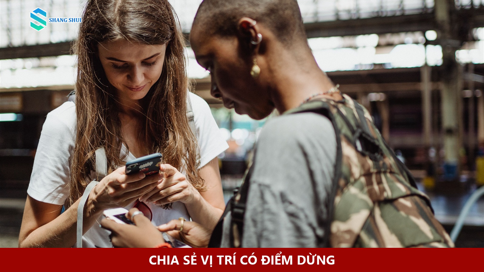Hai người mang ba lô cùng kiểm tra điện thoại ở nhà ga.