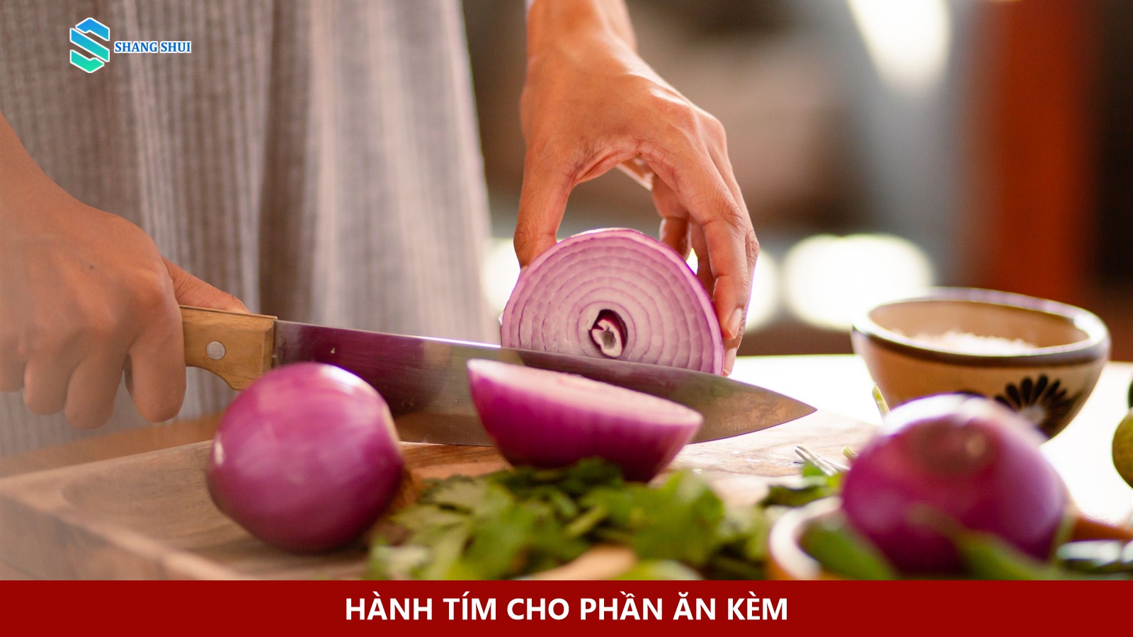 Bàn tay cắt hành tím trên thớt gỗ.