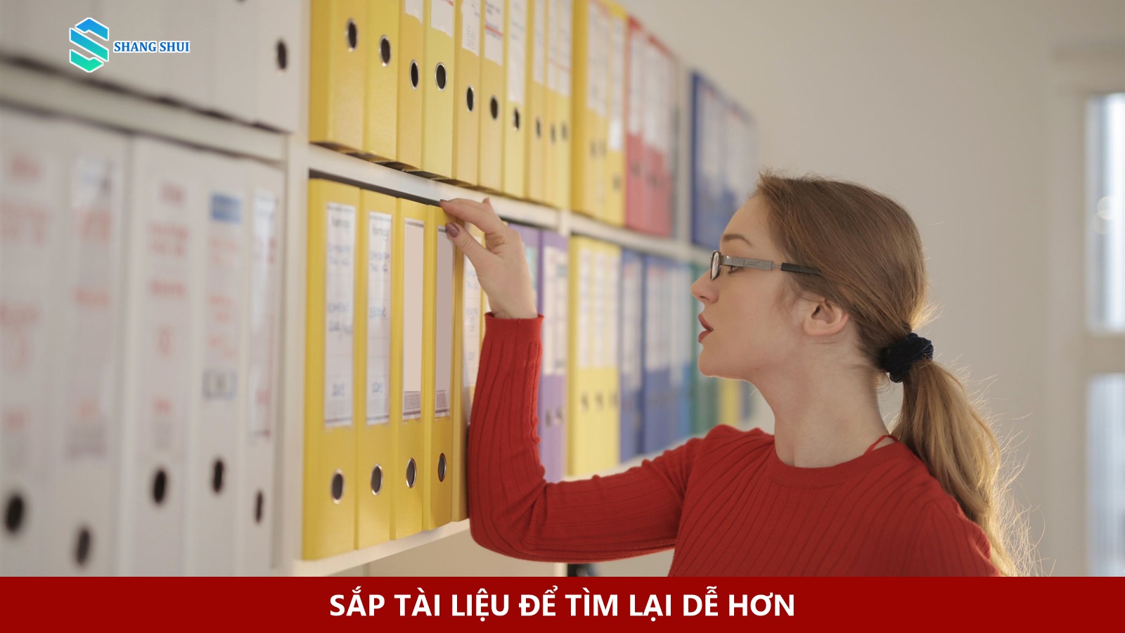 Người phụ nữ lấy một bìa hồ sơ từ hàng tài liệu trên kệ.