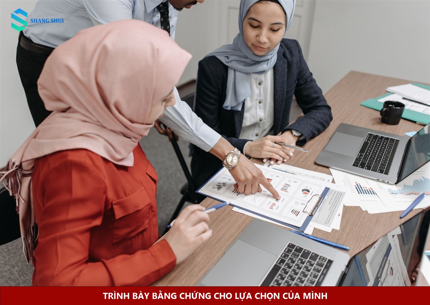 Hai người đối chiếu tài liệu và laptop khi trình bày kết quả công việc