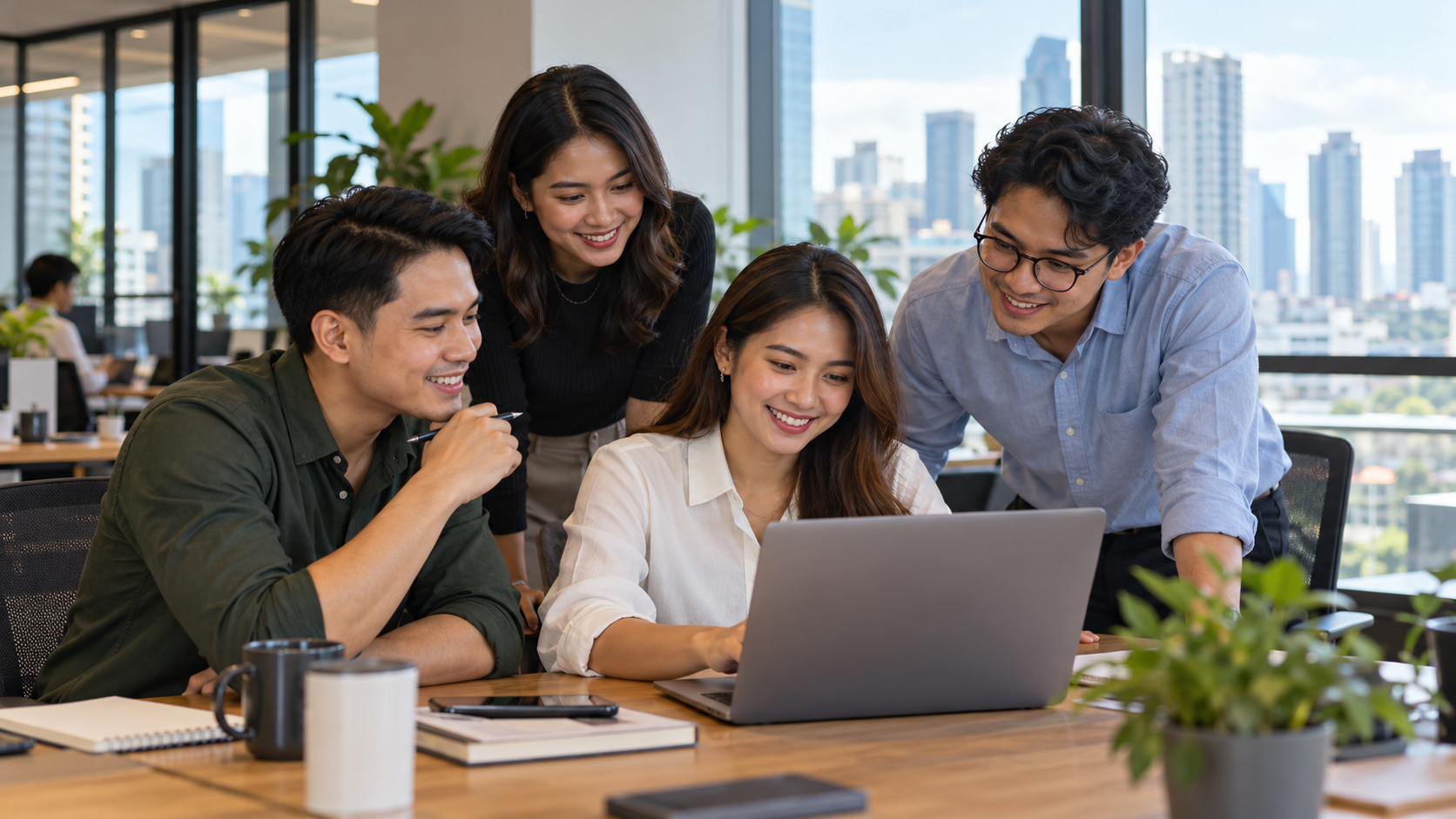 Bốn đồng nghiệp trao đổi quanh một laptop trong văn phòng sáng.